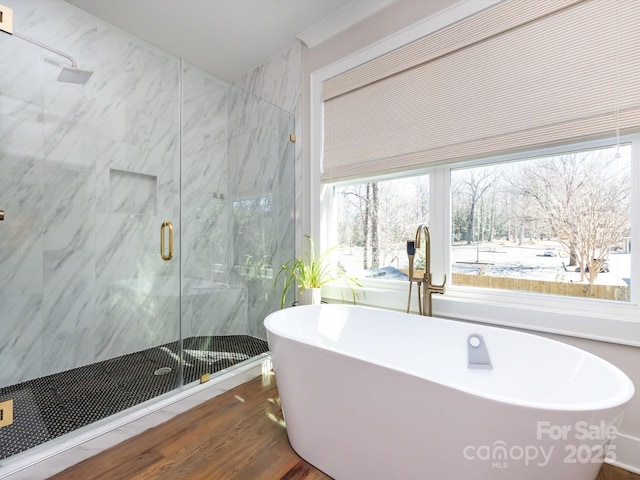 bathroom with wood finished floors, a freestanding tub, and a marble finish shower