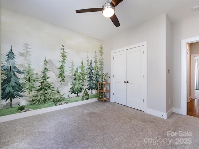 unfurnished bedroom with carpet floors, a ceiling fan, baseboards, and a closet