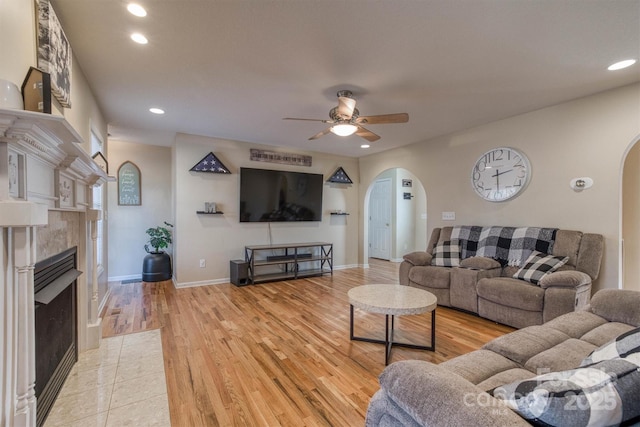 living room featuring ceiling fan, a fireplace, and light hardwood / wood-style flooring