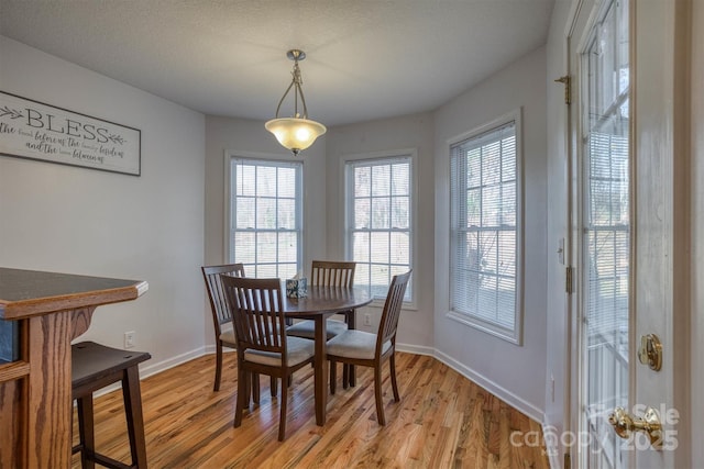 dining space with a textured ceiling and light hardwood / wood-style flooring