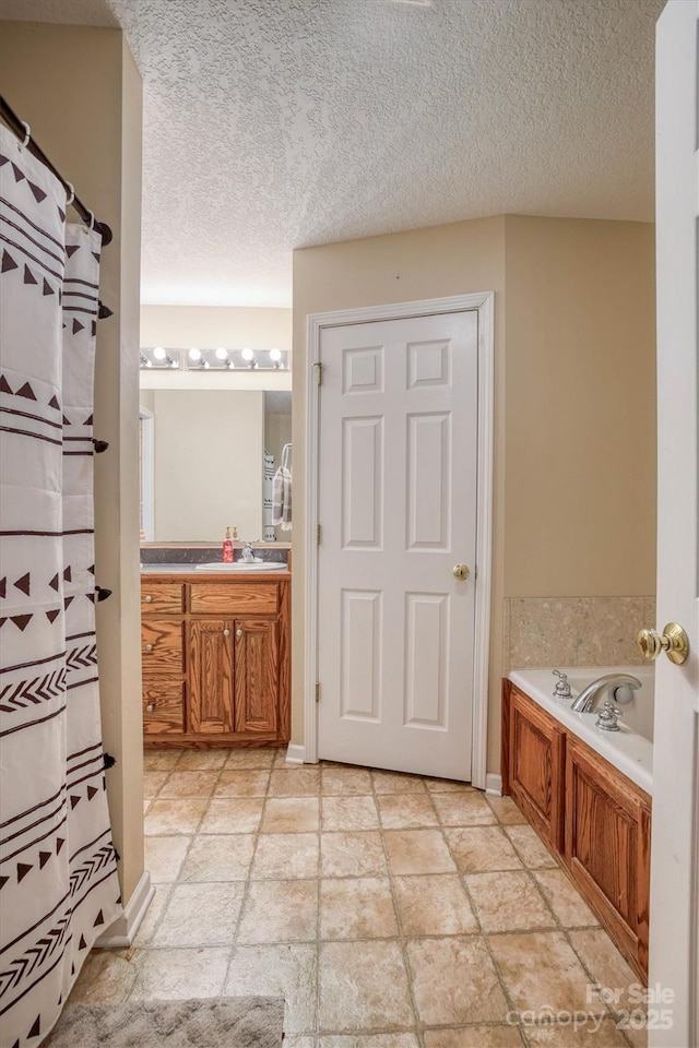 bathroom with a washtub, a textured ceiling, and vanity