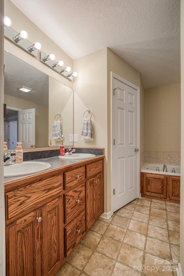 bathroom with a bathing tub, vanity, and a textured ceiling