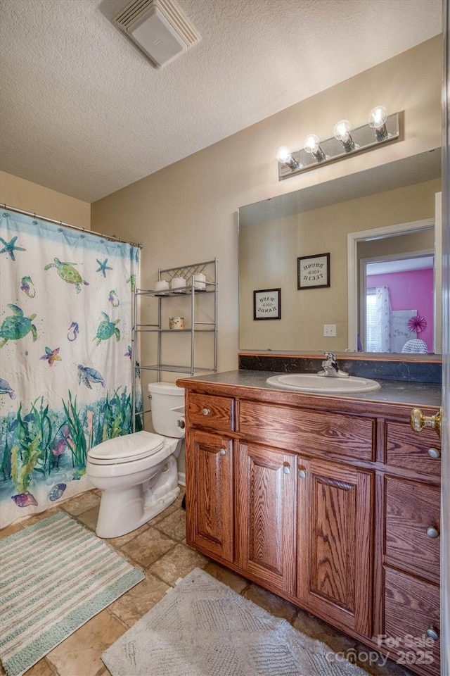 bathroom featuring a textured ceiling, vanity, and toilet