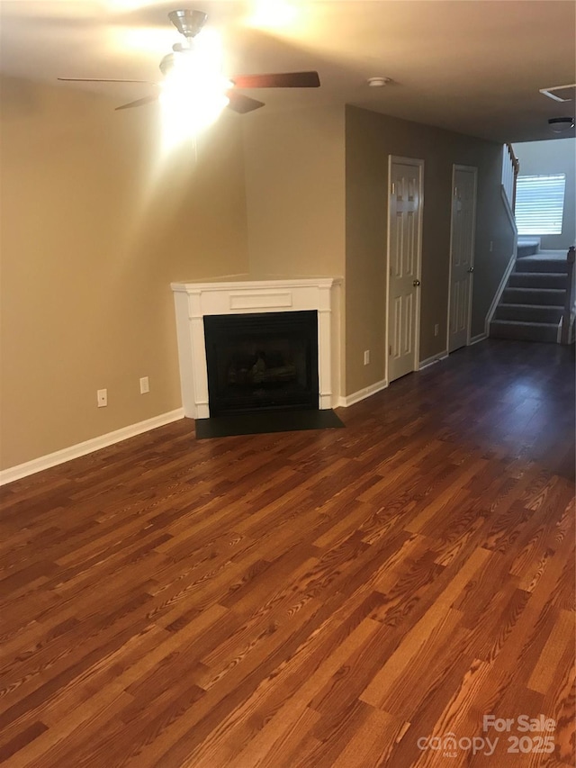 unfurnished living room with ceiling fan and dark wood-type flooring