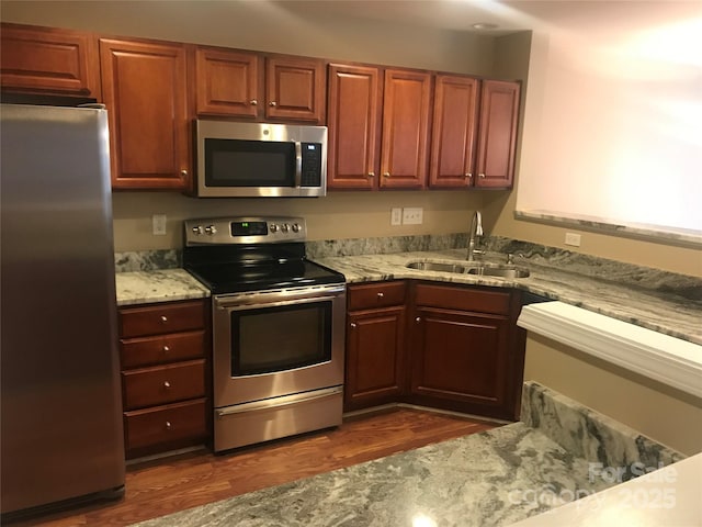 kitchen featuring light stone countertops, sink, dark wood-type flooring, and appliances with stainless steel finishes