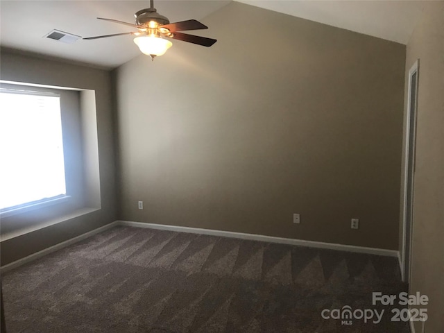 empty room featuring dark colored carpet, ceiling fan, a healthy amount of sunlight, and lofted ceiling