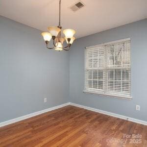 empty room with hardwood / wood-style floors and a notable chandelier