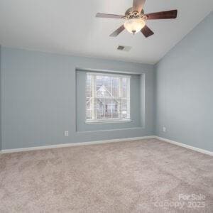 carpeted spare room featuring lofted ceiling and ceiling fan