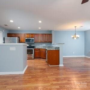 kitchen with stainless steel appliances, backsplash, light hardwood / wood-style floors, and decorative light fixtures