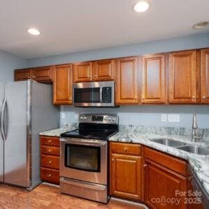 kitchen with appliances with stainless steel finishes, light stone countertops, and sink