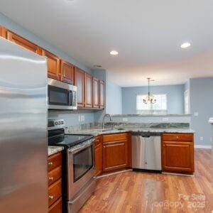 kitchen featuring stainless steel appliances, decorative light fixtures, sink, and light wood-type flooring