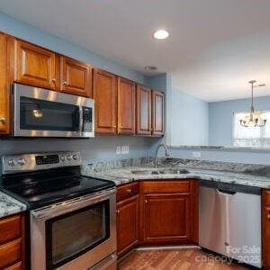 kitchen with sink, light stone counters, a chandelier, stainless steel appliances, and light hardwood / wood-style floors