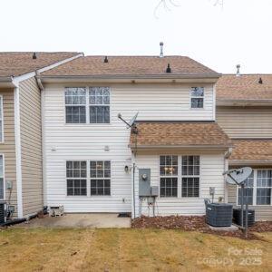 rear view of house with central AC and a yard