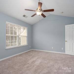 carpeted empty room featuring vaulted ceiling and ceiling fan