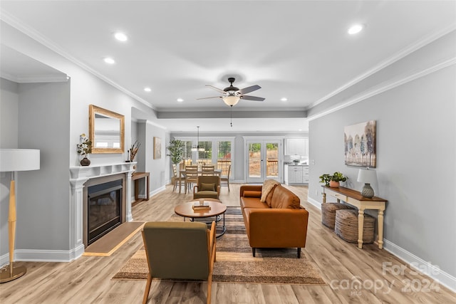 living room featuring ceiling fan, ornamental molding, and light hardwood / wood-style flooring