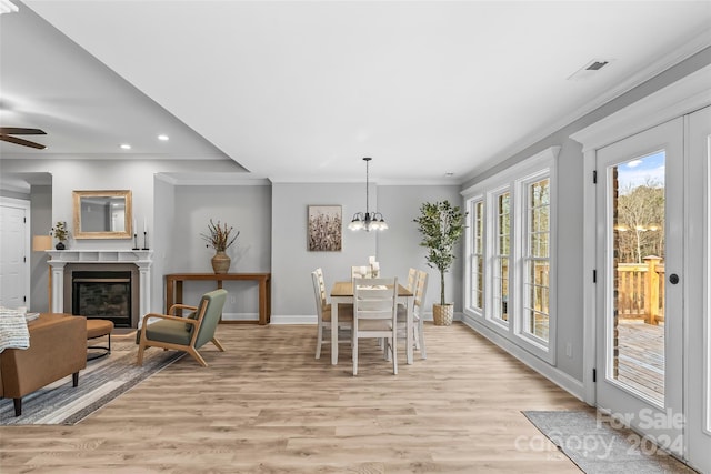 dining space with crown molding, ceiling fan with notable chandelier, and light wood-type flooring