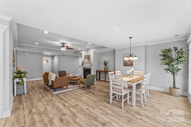 dining space featuring ceiling fan with notable chandelier, light wood-type flooring, and crown molding