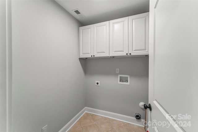 laundry room featuring electric dryer hookup, hookup for a washing machine, light tile patterned floors, and cabinets