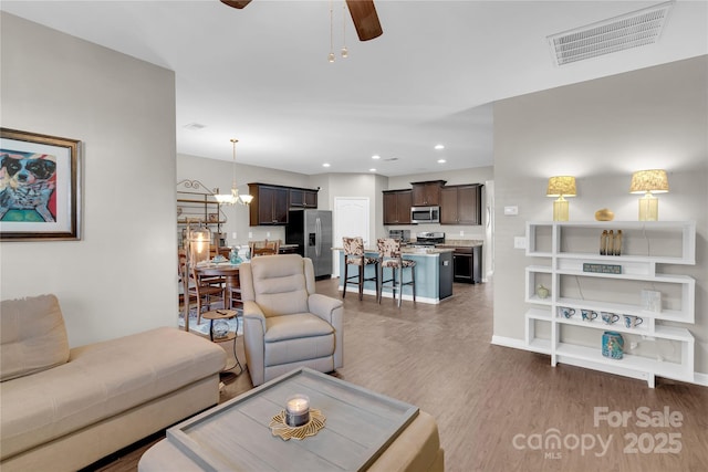 living room with dark hardwood / wood-style flooring and ceiling fan with notable chandelier