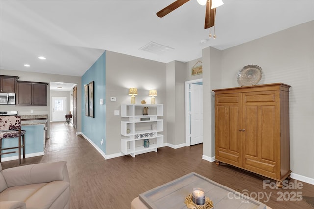 living room featuring ceiling fan and dark wood-type flooring