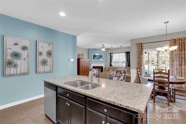 kitchen with dishwasher, a kitchen island with sink, ceiling fan with notable chandelier, sink, and decorative light fixtures