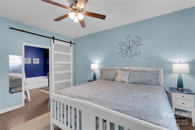 bedroom featuring ceiling fan, a barn door, and wood-type flooring