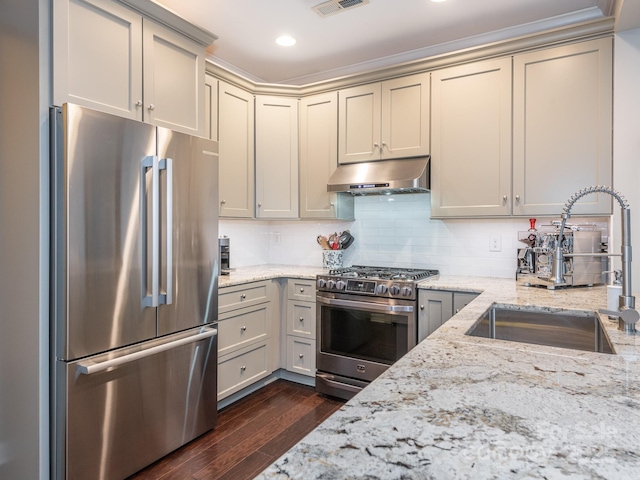 kitchen featuring high quality appliances, sink, and light stone counters