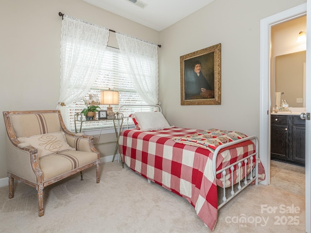 bedroom with ensuite bath and light carpet