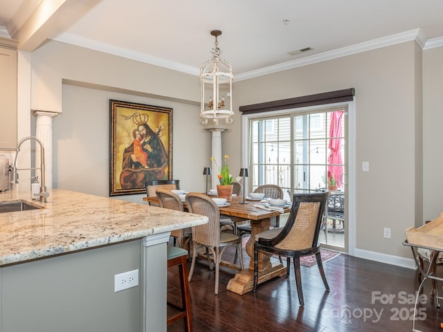 dining room with dark hardwood / wood-style flooring, ornamental molding, sink, and ornate columns