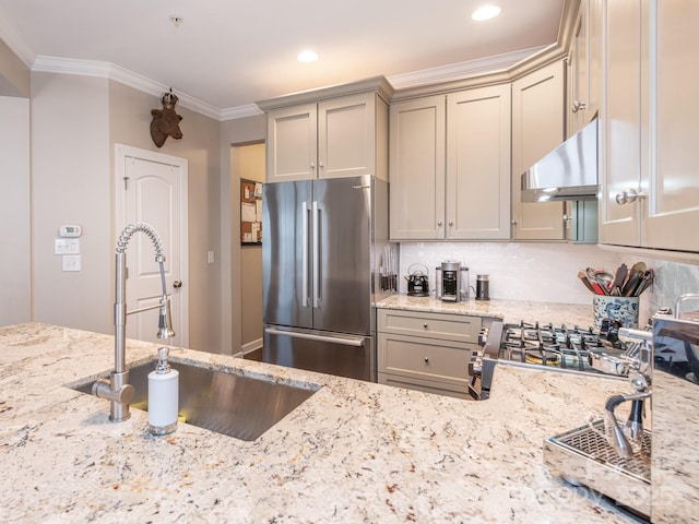 kitchen with stainless steel fridge, sink, light stone countertops, and ornamental molding