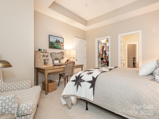 bedroom with a tray ceiling, a spacious closet, a closet, and light colored carpet