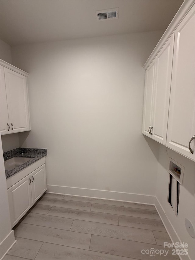 washroom with washer hookup, cabinets, sink, and light hardwood / wood-style flooring