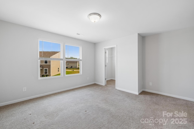 unfurnished bedroom with a walk in closet, light carpet, and a closet