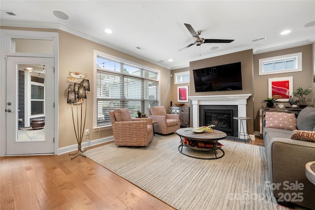 living room featuring crown molding, ceiling fan, and light wood-type flooring