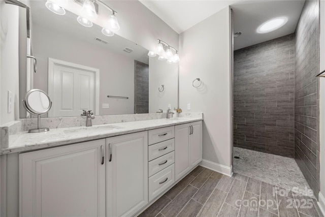 bathroom with a tile shower and vanity