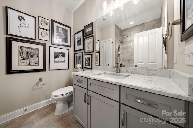 bathroom featuring toilet, vanity, and tiled shower