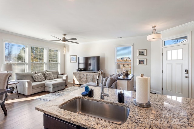 kitchen with light stone countertops, sink, ceiling fan, and pendant lighting