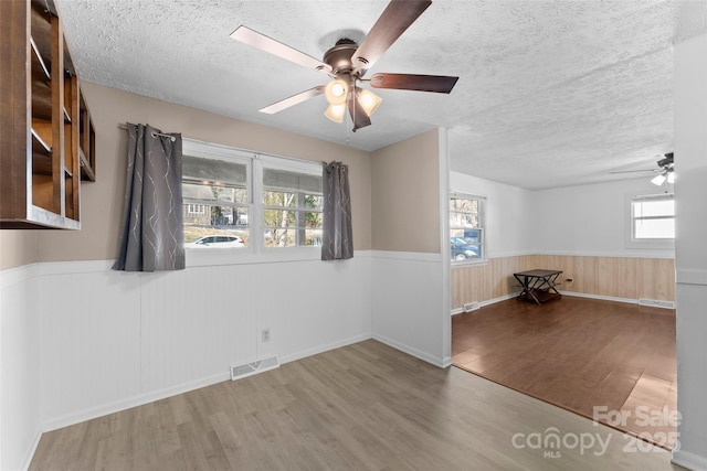 empty room with ceiling fan, wood-type flooring, and a textured ceiling