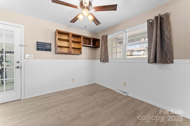 spare room featuring light wood-type flooring, ceiling fan, and wood walls