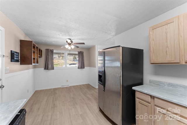 kitchen with a textured ceiling, light brown cabinetry, and stainless steel refrigerator with ice dispenser