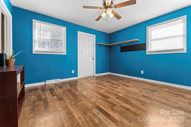 unfurnished bedroom featuring ceiling fan, dark wood-type flooring, and a textured ceiling