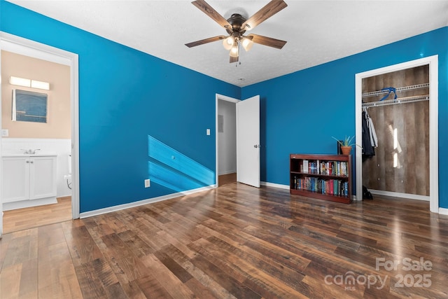 unfurnished bedroom featuring a closet, ceiling fan, dark hardwood / wood-style flooring, and a textured ceiling