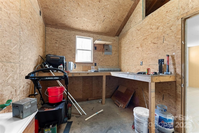 miscellaneous room featuring a workshop area, electric panel, concrete flooring, and lofted ceiling