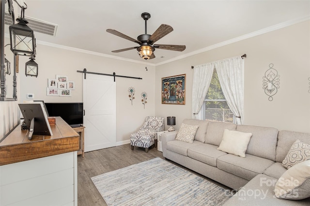 living room featuring ceiling fan, ornamental molding, a barn door, and hardwood / wood-style floors