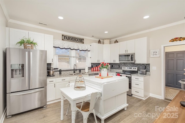 kitchen featuring white cabinetry, light hardwood / wood-style floors, stainless steel appliances, light stone countertops, and sink