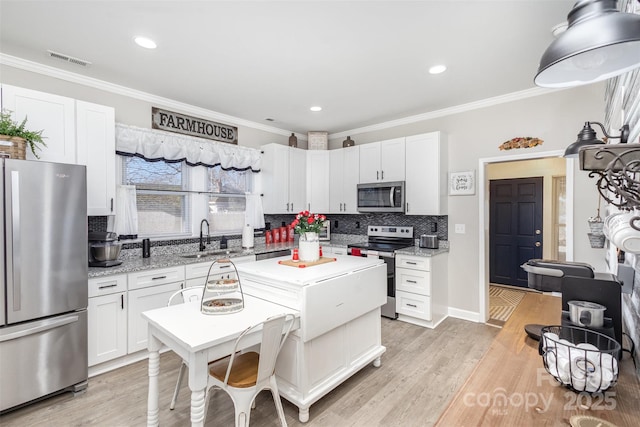 kitchen with white cabinetry, light hardwood / wood-style floors, appliances with stainless steel finishes, light stone countertops, and sink