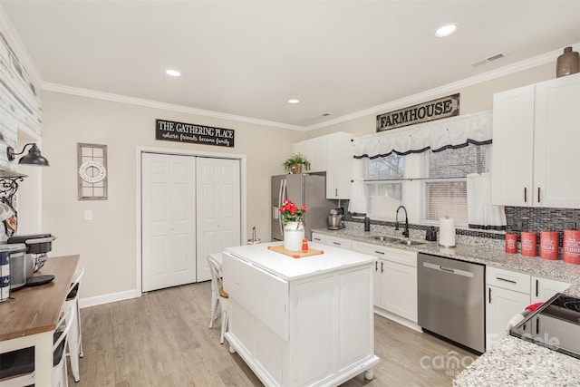 kitchen with light stone countertops, appliances with stainless steel finishes, sink, and white cabinetry