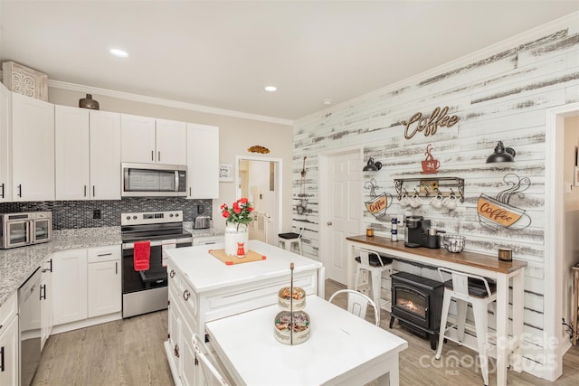 kitchen with tasteful backsplash, a center island, light wood-type flooring, appliances with stainless steel finishes, and white cabinets