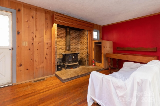 living room featuring wood-type flooring, a wood stove, and a textured ceiling