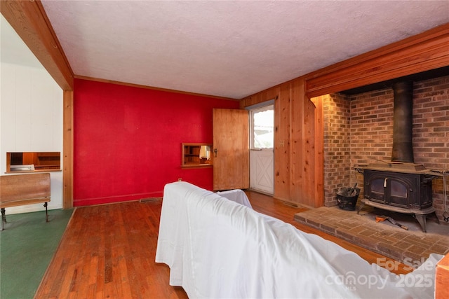 living room with a wood stove, crown molding, dark wood-type flooring, and a textured ceiling